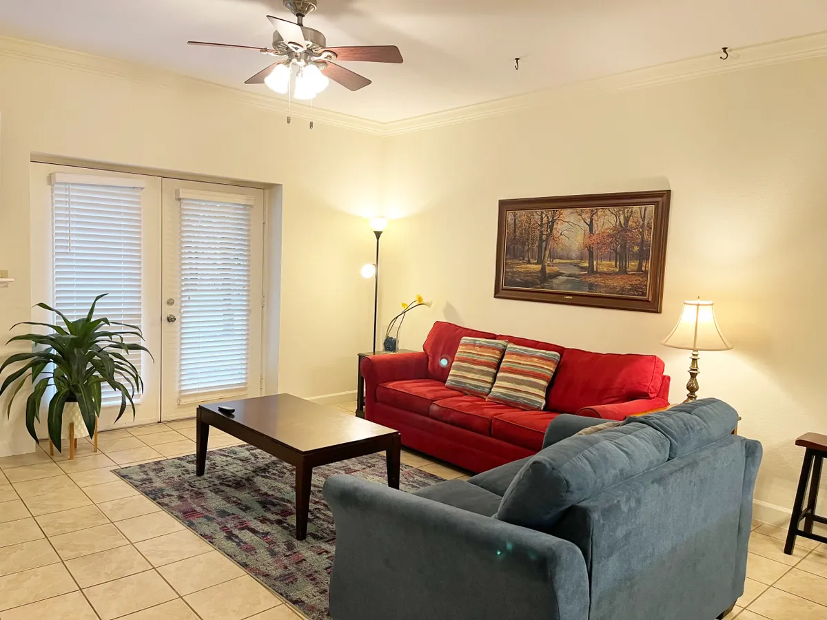 A welcoming living area showcasing a red and blue sofa, a coffee table, wall artwork, and a floor lamp. The space invites relaxation, socializing, or enjoying a morning coffee, reflecting the flexibility of the sleeper sofa.